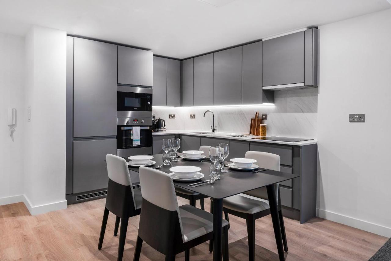 Citysuites 2 Aparthotel Μάντσεστερ Εξωτερικό φωτογραφία The photo shows a modern kitchen and dining area. The kitchen features sleek, gray cabinetry and a countertop that complements the overall aesthetic. There are built-in appliances, including an oven and refrigerator, arranged neatly. Next to the kitc