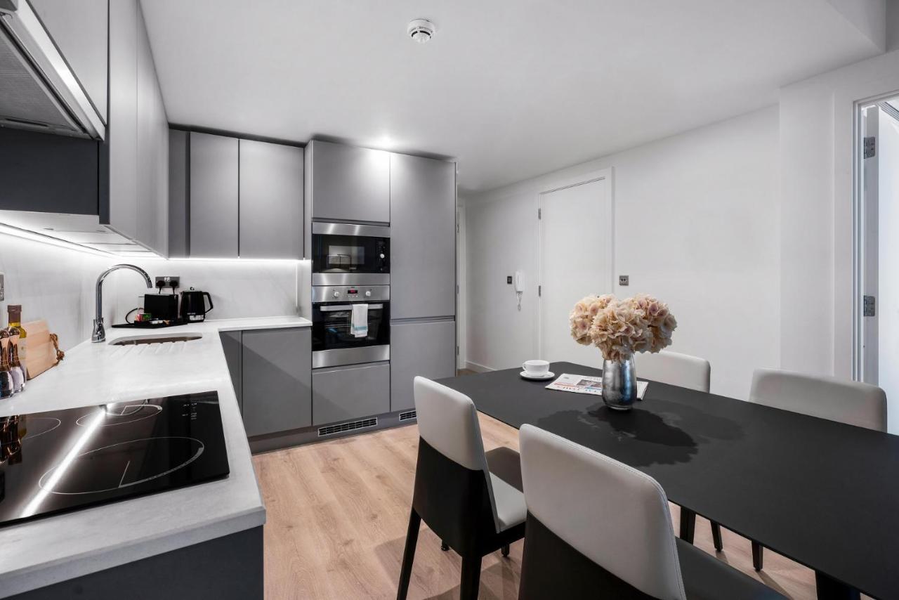 Citysuites 2 Aparthotel Μάντσεστερ Εξωτερικό φωτογραφία The photo shows a modern kitchen and dining area. The kitchen features sleek gray cabinets, a countertop with an embedded cooktop, and built-in appliances, including an oven and microwave. There’s a small coffee maker on the counter. Adjacent to the 