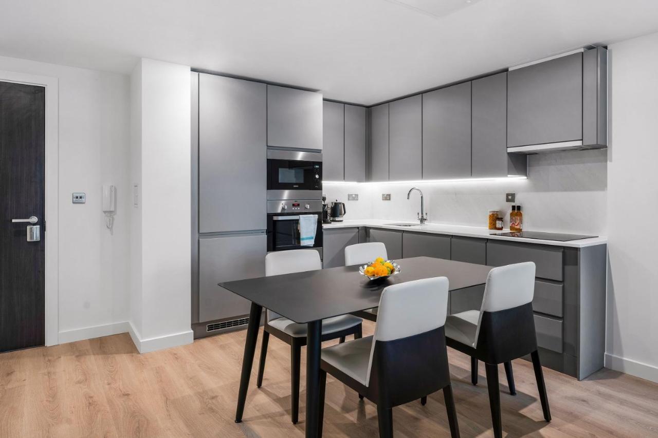 Citysuites 2 Aparthotel Μάντσεστερ Εξωτερικό φωτογραφία The photo shows a modern kitchen with a sleek and minimalist design. The cabinetry features a gray finish, and there are built-in appliances, including an oven and possibly a microwave. The countertop is light-colored, providing contrast to the darke