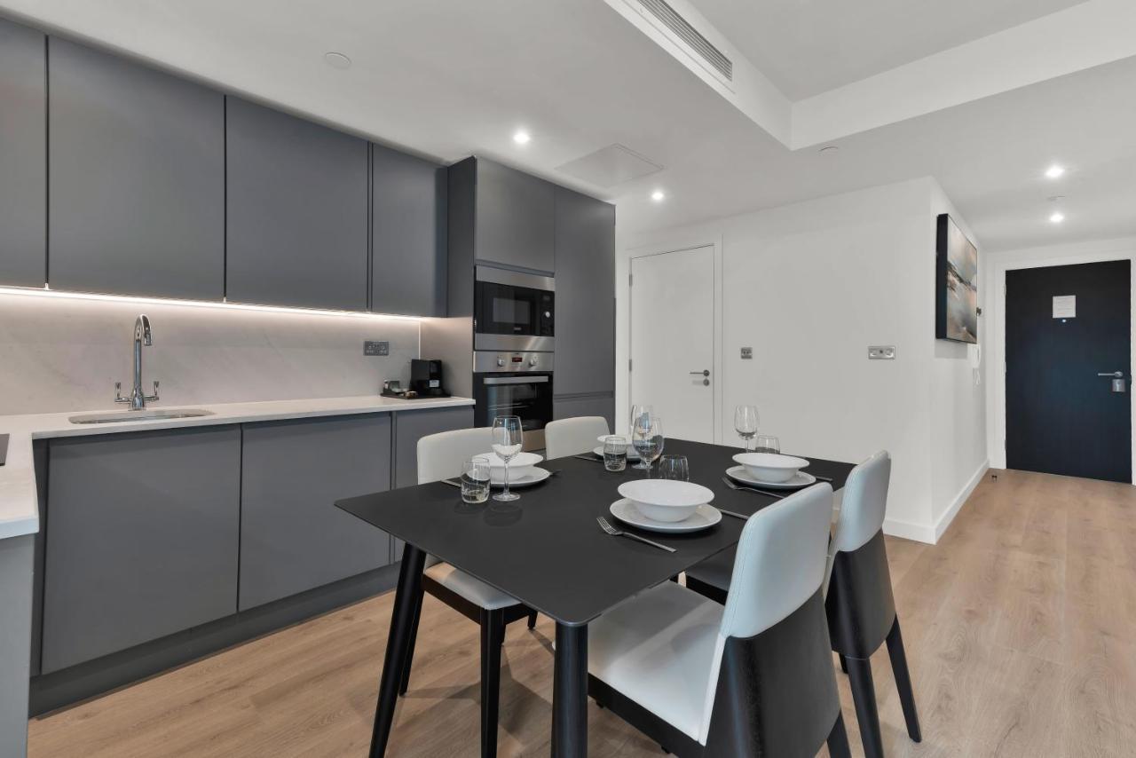 Citysuites 2 Aparthotel Μάντσεστερ Εξωτερικό φωτογραφία The photo shows a modern kitchen and dining area. There are sleek gray cabinetry and countertops, with a built-in oven and microwave. The kitchen is well-lit, featuring under-cabinet lighting that adds to the contemporary feel. In the dining area, th