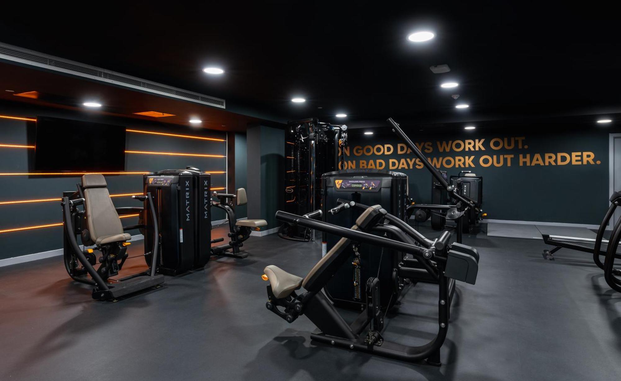 Citysuites 2 Aparthotel Μάντσεστερ Εξωτερικό φωτογραφία The photo shows a modern gym interior. The gym features various exercise machines, including weight training equipment. The flooring is dark, and the walls are adorned with motivational text that reads, "ON GOOD DAYS WORK OUT. ON BAD DAYS WORK OUT HA
